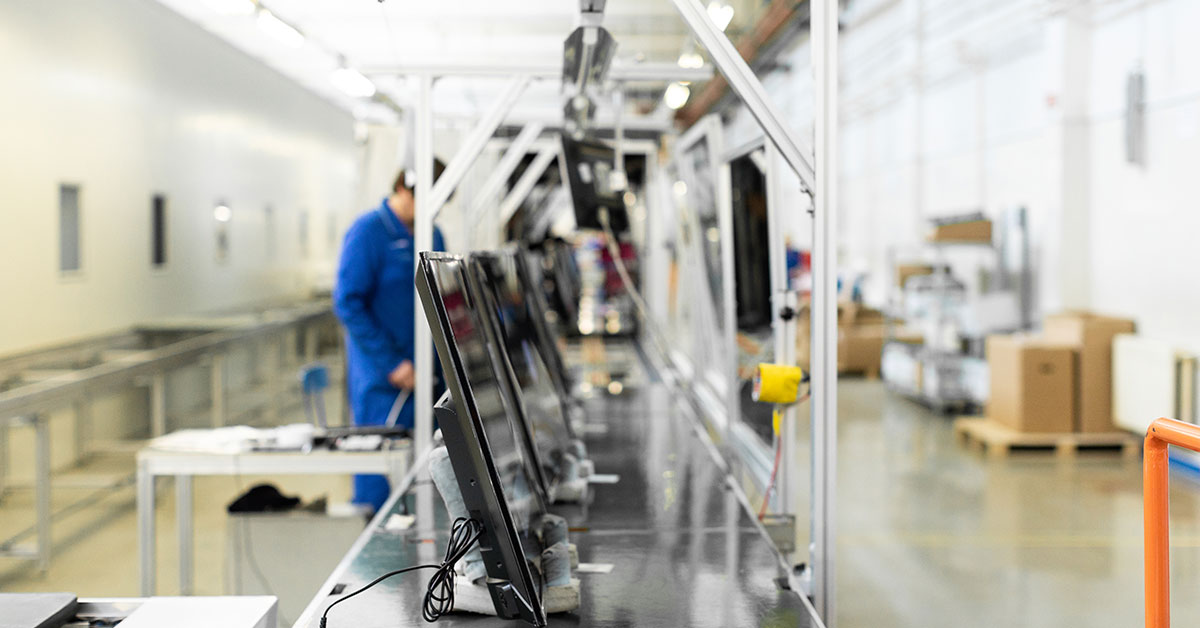 Assembly line with flat-screen monitors in a factory setting, representing small business growth and funding opportunities through business loans
