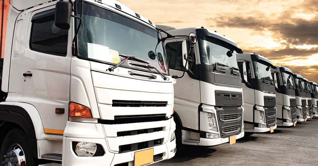 Fleet of commercial trucks parked in a row at sunset, symbolizing transportation business and financing opportunities through credit unions