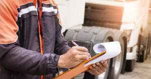 Commercial truck operator conducting an inspection and taking notes, highlighting the importance of truck maintenance and repair financing