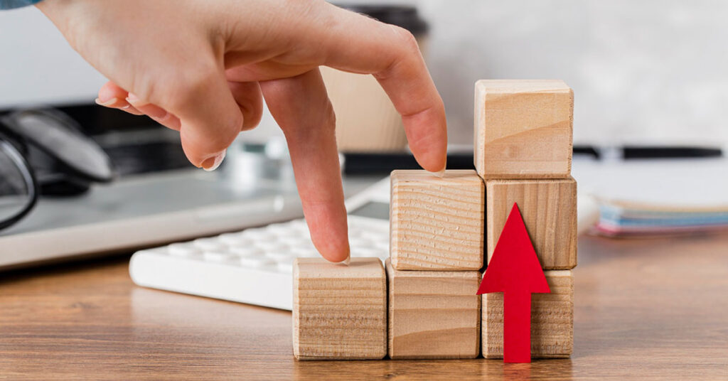 Hand walking up wooden blocks with an upward arrow symbolizing business growth, progress, and scaling success