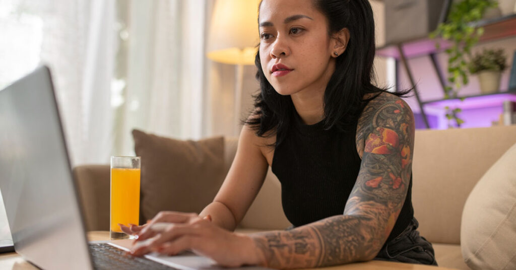Focused freelancer working on a laptop from home with a glass of juice nearby, representing independent work and remote career flexibility