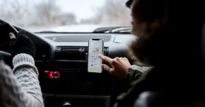 People traveling by car while using a GPS application on a smartphone mounted on the dashboard to search for directions or a restaurant location.