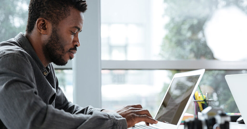 Focused entrepreneur working on a laptop in a modern office, researching financing tips and strategies to quickly start a small business.