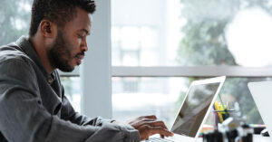 Focused entrepreneur working on a laptop in a modern office, researching financing tips and strategies to quickly start a small business.