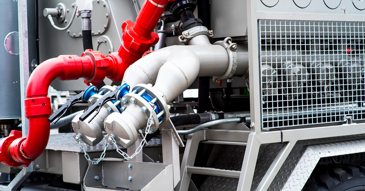 Close-up of industrial construction pump system with red and silver pipes and valve connections—illustrating key components to consider when selecting a pump for a construction job.