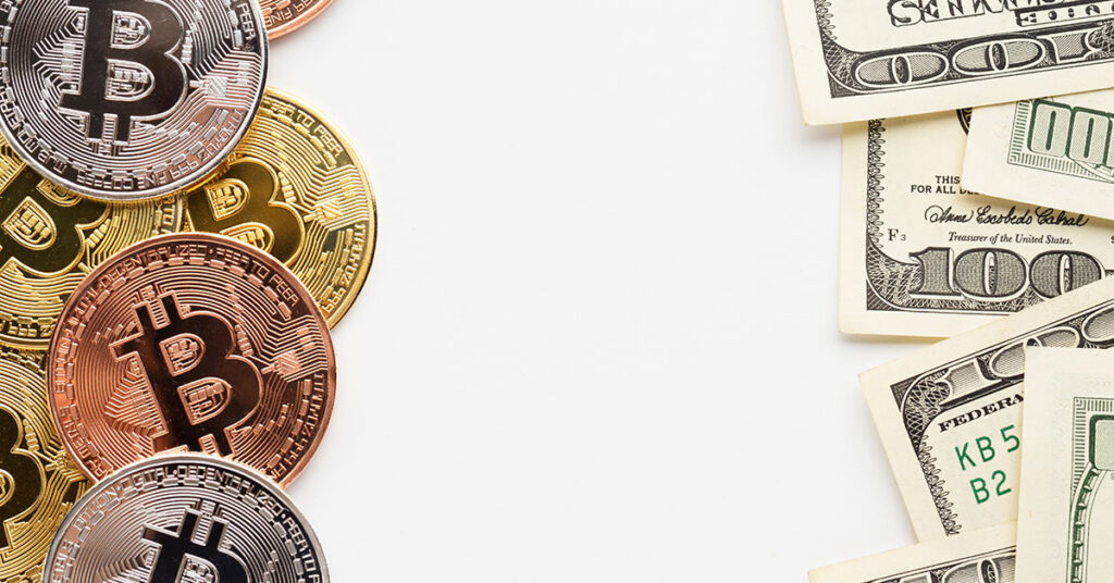Arrangement of physical Bitcoin tokens next to U.S. dollar bills—symbolizing the comparison between cryptocurrency and traditional currency for business use.