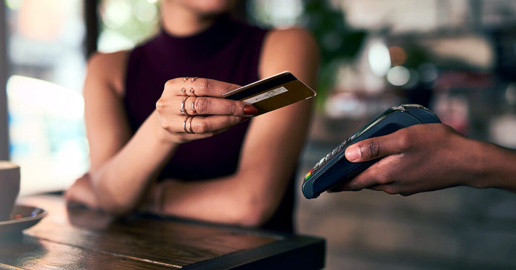Customer making a contactless credit card payment at a café—illustrating the convenience and benefits of accepting card payments in small businesses.