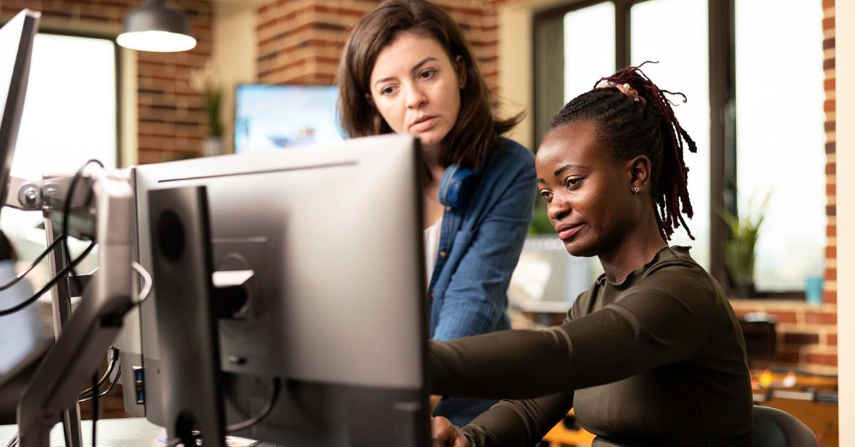 Two businesswomen collaborating at a computer in a modern office—illustrating CRM training and team development for small business sales success.