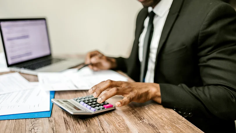 Man on a desktop using a calculator