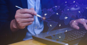 Businessman using a laptop with a digital world map and flight routes overlay, symbolizing international business expansion and global tax considerations.