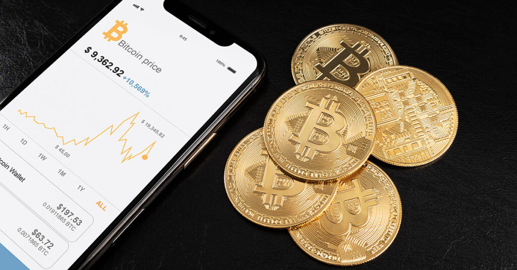 Smartphone displaying Bitcoin price chart alongside golden Bitcoin coins on black background, representing cryptocurrency adoption in business payments.