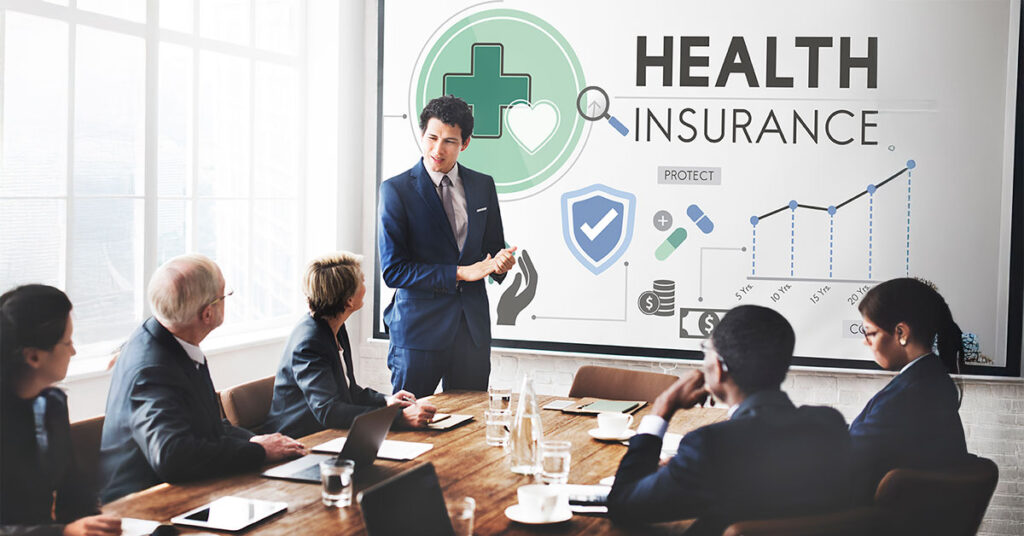 Business team attending a presentation on health insurance strategies and employee benefits, highlighting cost-effective healthcare solutions for small businesses.