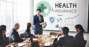 Business team attending a presentation on health insurance strategies and employee benefits, highlighting cost-effective healthcare solutions for small businesses.