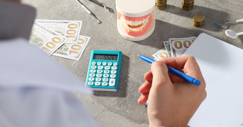Close-up of dentist calculating financial costs with dental tools, money, and a dental model on the table, representing the financial planning involved in dental practice management.