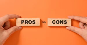 Two hands holding wooden blocks labeled “Pros” and “Cons” on an orange background—symbolizing the comparison of business loan options.